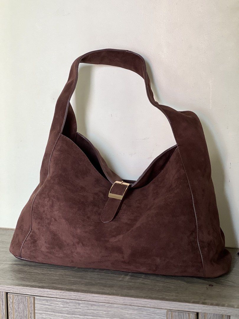 Secosana Brown Suede Shoulder Hobo Bag (Category: Shoulder Bags) located in Pili. Submitted by gaellecast (Listing ID 1464969187, Image 1). Description: - Brand: Secosana - Material: Rich brown suede with soft, slouchy body - Hardware: Gold-toned throughout - Pockets: Exterior zippered pocket and fabric-lined interior with an additional zippered pocket - Closure: Front buckle accent with metallic snap button - Strap: Comfortable shoulder strap in