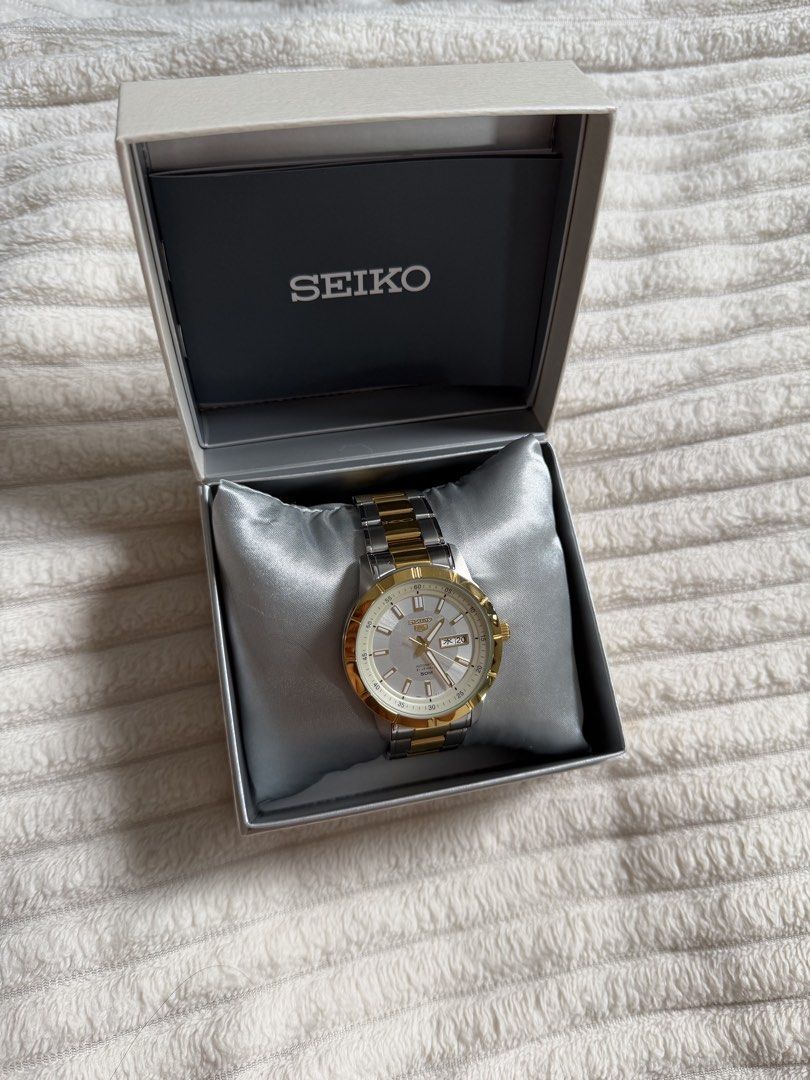 Seiko 5 Automatic Two-Tone Watch with Box (Category: Men's Watches) located in Manila. Submitted by tedranes (Listing ID 1465050983, Image 2). Description: - Brand: Seiko 5 Automatic - Dial/Bezel: Silver dial with gold bezel - Bracelet: Two-tone stainless steel and gold - Features: Day and date display at 3 o'clock - Condition: Brand new, never worn, pristine condition - Inclusions: Official box, manual, and warranty card (dated August 2026) - ne