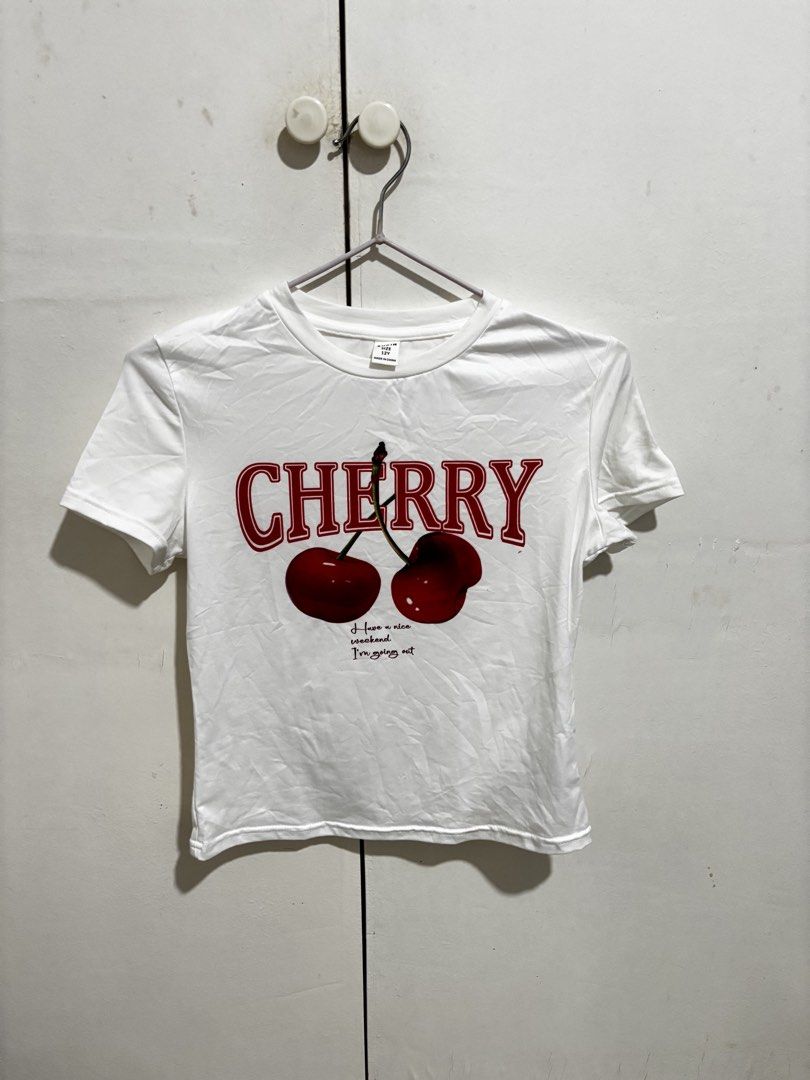 Shein Cherry Graphic White T-shirt (Category: Shirts) located in Manila. Submitted by dianafayesimbre (Listing ID 1465072291, Image 2). Description: White short-sleeve tee from Shein. Red cherry graphic print on the front with text lettering. Round neckline. Size 12Y tag on tag but can fit xs to semi medium womens. Plain solid white back. Lightweight fabric, easy to style with jeans or skirts..