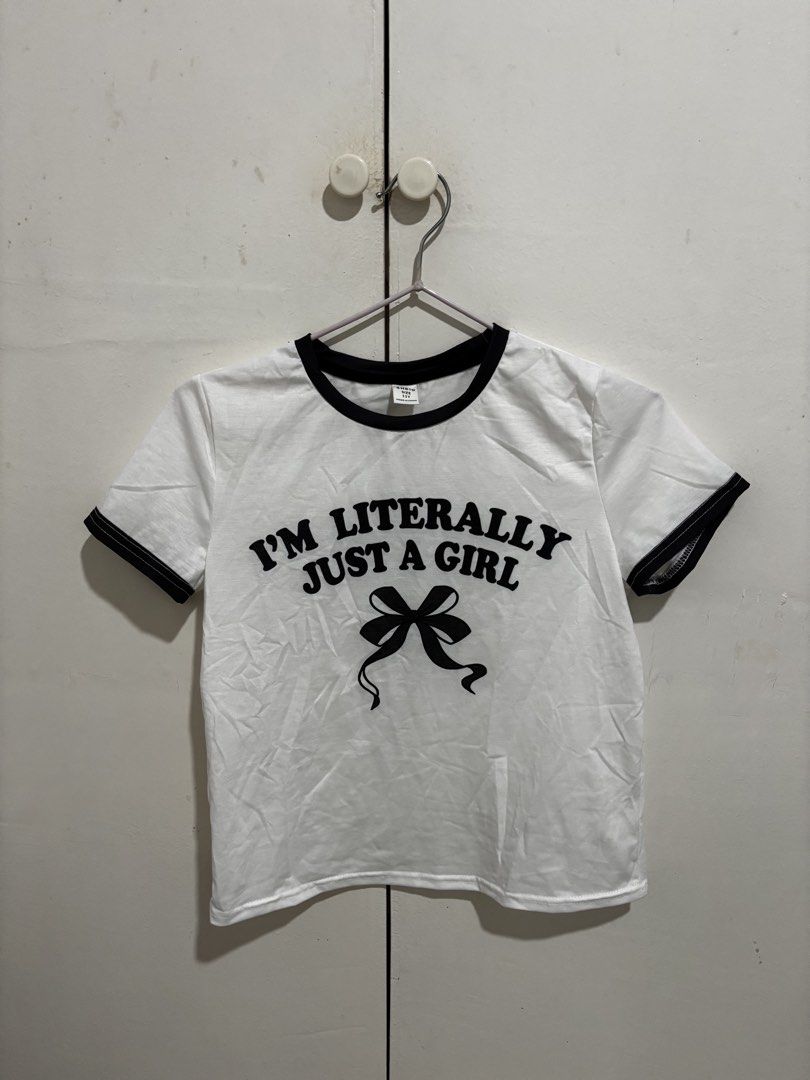 Shein White Ringer Graphic Shirt (Category: Shirts) located in Manila. Submitted by dianafayesimbre (Listing ID 1465072748, Image 1). Description: - Brand: Shein - Size: 11Y on tag but can fit xs to medium - Color: White with black contrast trim on collar and sleeves - Design: Front graphic reads 'I'm literally just a girl' with a black ribbon bow underneath (plain back) - Fabric: Lightweight and comfortable.