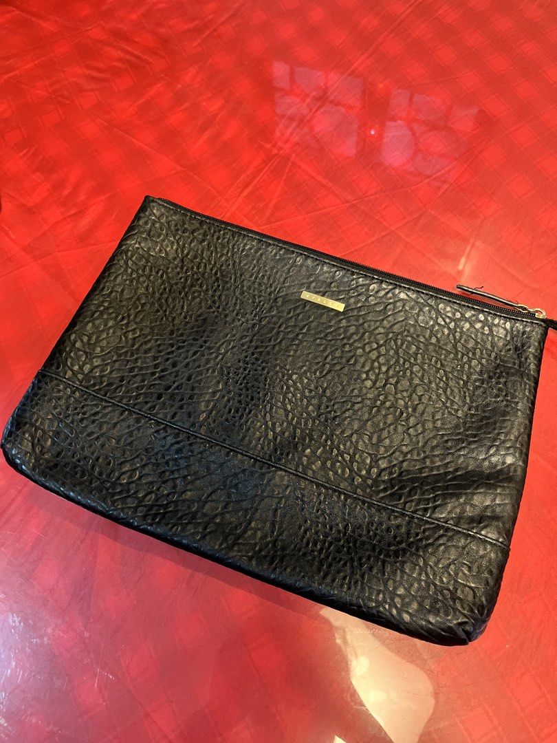 Sisley Black Textured Pouch Clutch (Category: Clutches) located in Manila. Submitted by harpymonetttt (Listing ID 1465104800, Image 1). Description: - Brand: Sisley - Material: Black faux leather with a textured pebble finish - Hardware: Gold-tone Sisley logo plate on front - Closure: Top zipper with dark pull tab - Interior: Fully lined with black fabric, includes one open slip pocket - Condition: Clean interior and exterior, excellent pre-loved