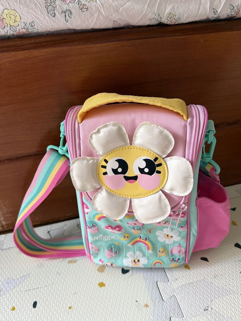 Smiggle Flower Lunch Box Bag with Rainbow Strap (Category: Shoulder Bags) located in Cebu City. Submitted by limjennif52235 (Listing ID 1464979865, Image 2). Description: - Authentic Smiggle insulated lunch bag in a mint green, pink, and yellow colorway - Features fun floral, rainbow, and ice cream graphics with a big smiling flower patch - Keeps food fresh with a silver insulated lining and includes a name tag label under the lid - Offers extra 