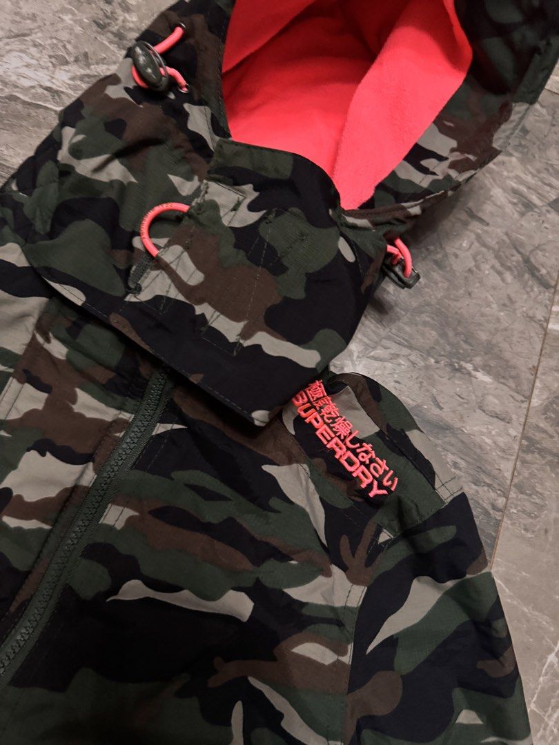 Superdry Professional The Windcheater Camo Jacket (Category: Coats, Jackets and Outerwear) located in Alaminos. Submitted by outfitcheck.ph (Listing ID 1465110296, Image 2). Description: Superdry Professional The Windcheater jacket in green camouflage pattern. Bright neon pink lining inside the hood and collar, matching pink embroidery details on the shoulder and back. Double zip closure with toggle pull cords. Ribbed inner collar for extra warmt