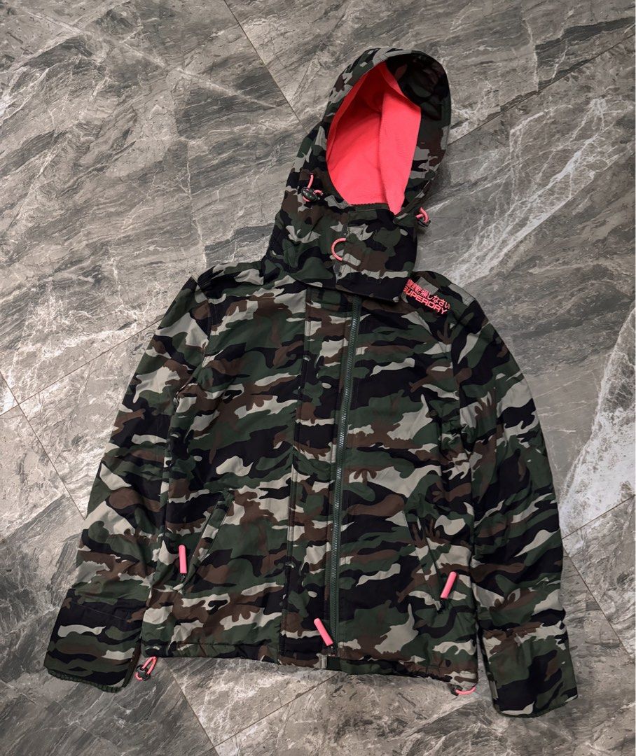 Superdry Professional The Windcheater Camo Jacket (Category: Coats, Jackets and Outerwear) located in Alaminos. Submitted by outfitcheck.ph (Listing ID 1465110296, Image 1). Description: Superdry Professional The Windcheater jacket in green camouflage pattern. Bright neon pink lining inside the hood and collar, matching pink embroidery details on the shoulder and back. Double zip closure with toggle pull cords. Ribbed inner collar for extra warmt