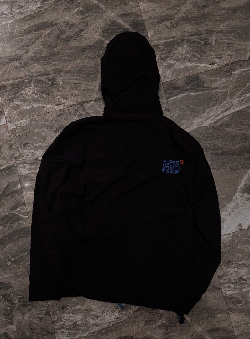 Superdry The Windhiker Jacket Black Blue Size M (Category: Coats, Jackets and Outerwear) located in Alaminos. Submitted by outfitcheck.ph (Listing ID 1465109768, Image 3). Description: - Brand: Superdry The Windhiker - Color: Black with bright blue inner fleece lining - Size: Medium (M) - Features: Full zip front, zippered chest pocket, and adjustable hood toggles - Details: Japanese character embroidery on storm flap and back right shoulder, plu