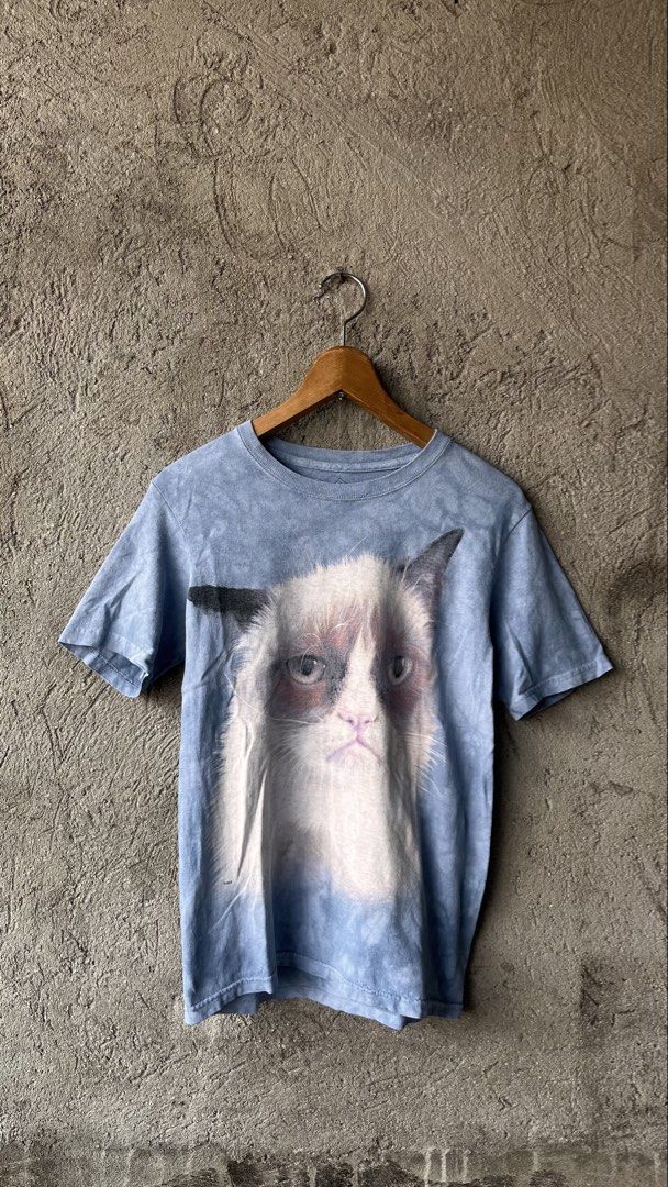 The Mountain Grumpy Cat Blue T-Shirt Size L (Category: Shirts) located in Cabuyao City. Submitted by bulandos (Listing ID 1465051827, Image 1). Description: - Design: Large Grumpy Cat portrait on the front with a light blue acid wash style - Size: Large (tag printed inside the collar) - Material: 100% classic heavy cotton for a comfortable, relaxed fit - Origin: Made in the USA with assembly in Mexico - Condition: Great quality graphic tee, perfe