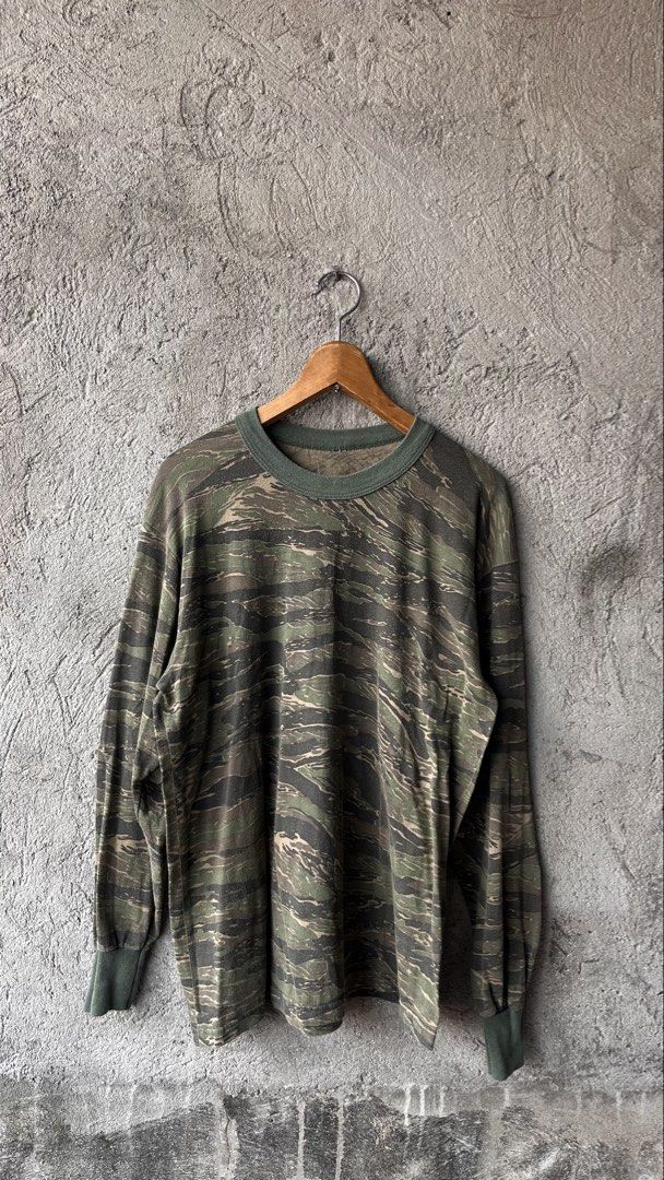 Tiger Stripe Camo Long Sleeve Shirt Crewneck (Category: Tshirts & Polo Shirts ) located in Cabuyao City. Submitted by bulandos (Listing ID 1465052182, Image 1). Description: - Design: Bold tiger stripe camouflage pattern all over - Style: Long sleeve crewneck with classic ribbed collar - Details: Contrast green ribbed trim on the neck and wrist cuffs - Condition: Shows some pilling throughout from regular wear and washing - Perfect for a rugged, 