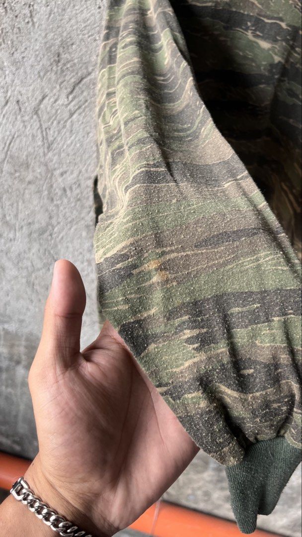 Tiger Stripe Camo Long Sleeve Shirt Crewneck (Category: Tshirts & Polo Shirts ) located in Cabuyao City. Submitted by bulandos (Listing ID 1465052182, Image 3). Description: - Design: Bold tiger stripe camouflage pattern all over - Style: Long sleeve crewneck with classic ribbed collar - Details: Contrast green ribbed trim on the neck and wrist cuffs - Condition: Shows some pilling throughout from regular wear and washing - Perfect for a rugged, 