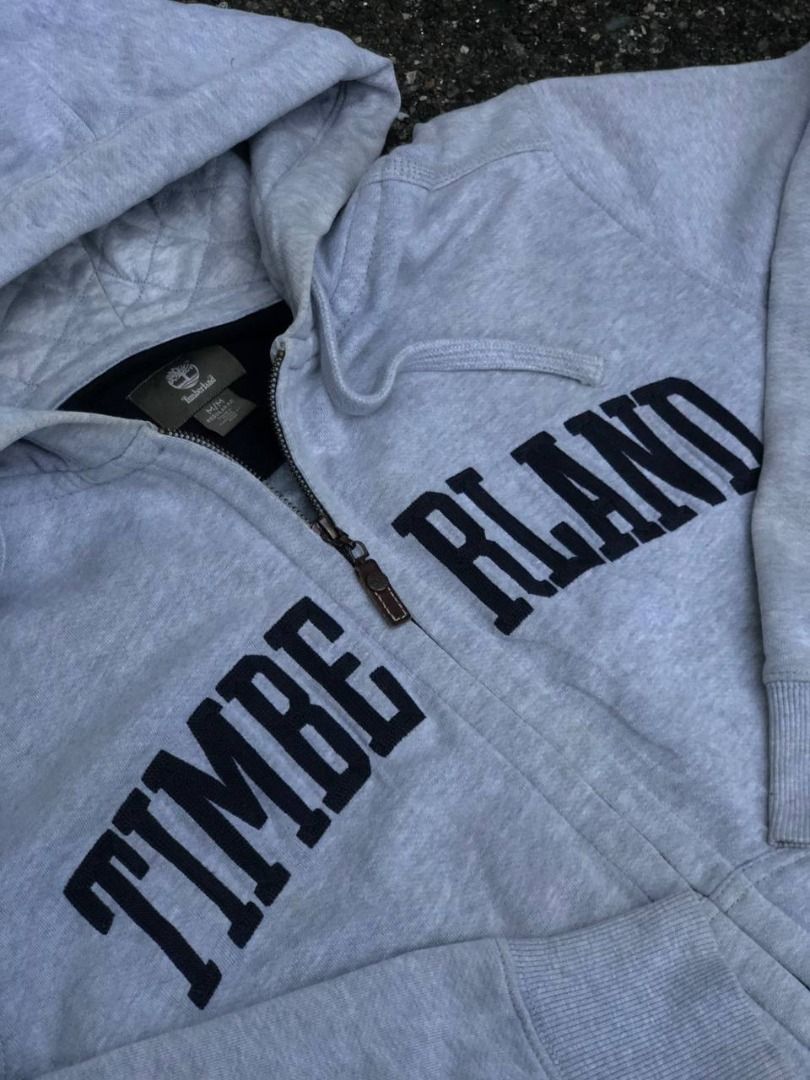 Timberland Grey Zip Hoodie (Category: Coats, Jackets and Outerwear) located in Tacloban City. Submitted by thedropout (Listing ID 1465053256, Image 2). Description: - Authentic Timberland grey zip-up hoodie - Size: Medium (Regular Fit) - Bold black letter branding across the front - Warm quilted hood lining with drawstring - Full zip closure with iconic tree-stamped leather pull - Convenient side pockets for daily essentials - Ribbed cuffs and he