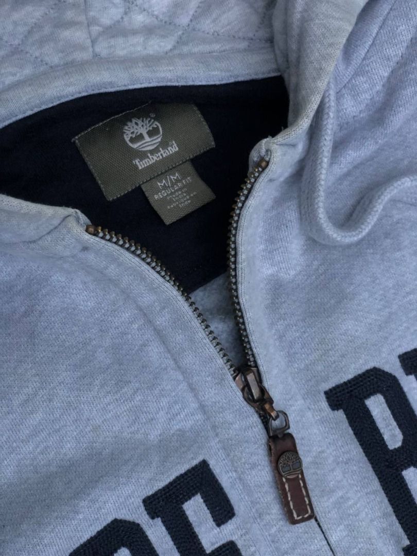 Timberland Grey Zip Hoodie (Category: Coats, Jackets and Outerwear) located in Tacloban City. Submitted by thedropout (Listing ID 1465053256, Image 3). Description: - Authentic Timberland grey zip-up hoodie - Size: Medium (Regular Fit) - Bold black letter branding across the front - Warm quilted hood lining with drawstring - Full zip closure with iconic tree-stamped leather pull - Convenient side pockets for daily essentials - Ribbed cuffs and he