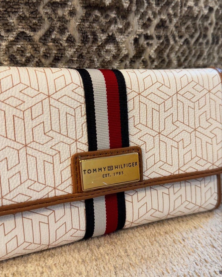 Tommy Hilfiger Monogram Long Wallet (Category: Wallets & Card holders) located in Manila. Submitted by luwiswisz (Listing ID 1465053492, Image 3). Description: - Brand: Tommy Hilfiger - Condition: Brand new with tag attached - Color/Pattern: White with geometric monogram, brown trim, and signature navy/white/red stripe - Hardware: Gold-tone with logo plate - Closure: Snap button - Interior: Multiple card slots, ID window, compartments, and black 