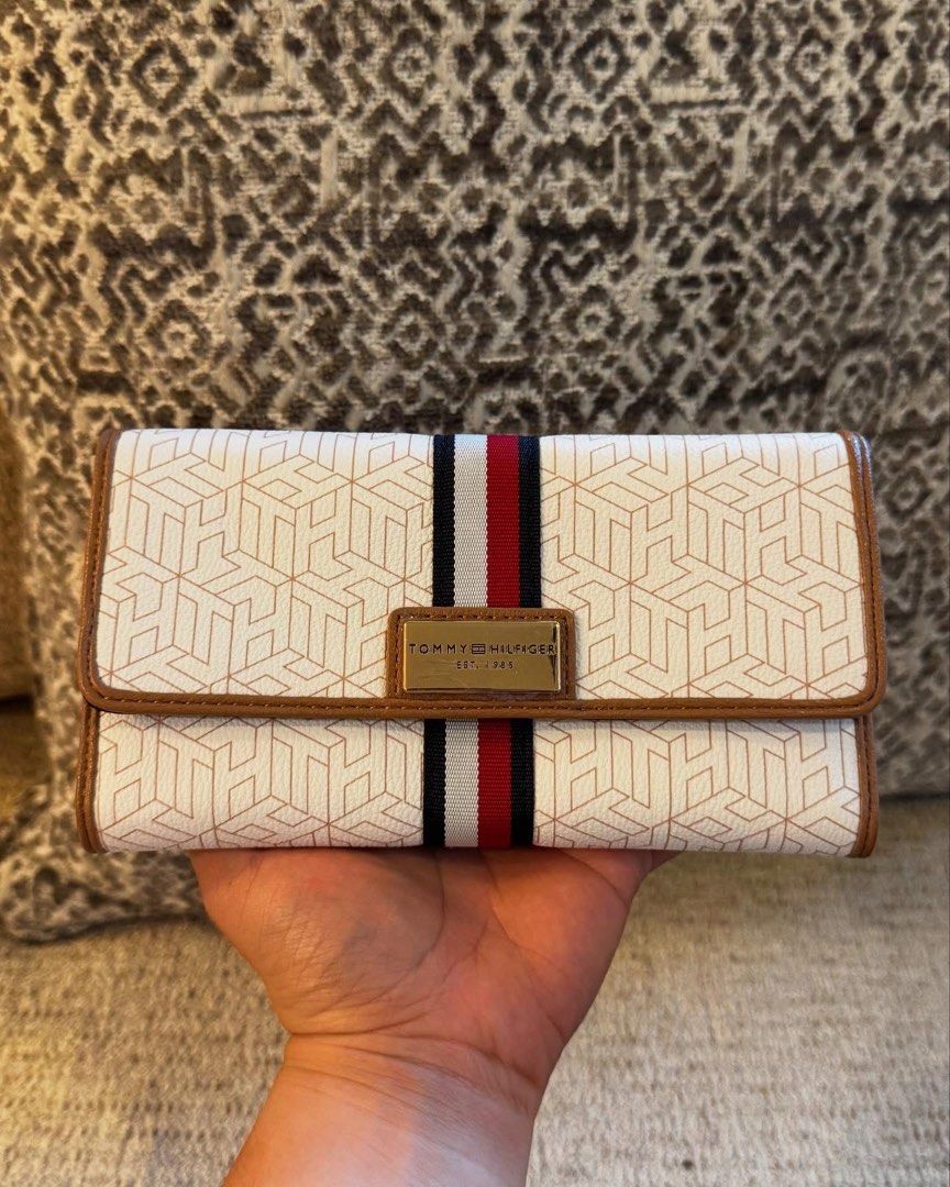 Tommy Hilfiger Monogram Long Wallet (Category: Wallets & Card holders) located in Manila. Submitted by luwiswisz (Listing ID 1465053492, Image 2). Description: - Brand: Tommy Hilfiger - Condition: Brand new with tag attached - Color/Pattern: White with geometric monogram, brown trim, and signature navy/white/red stripe - Hardware: Gold-tone with logo plate - Closure: Snap button - Interior: Multiple card slots, ID window, compartments, and black 