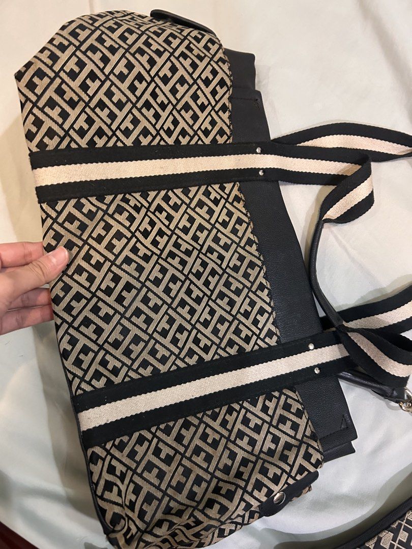 Tommy Hilfiger Monogram Tote Bag with Pouch (Category: Tote Bags) located in Quezon City. Submitted by retro_chic25 (Listing ID 1465087006, Image 2). Description: - Brand: Tommy Hilfiger - Set includes: Tote bag and matching small pouch - Design: Classic black and beige monogram pattern with black faux leather trim - Straps: Stylish striped shoulder straps with secure metal hardware - Interior: Navy lining, red-trimmed zip pocket, and red leather