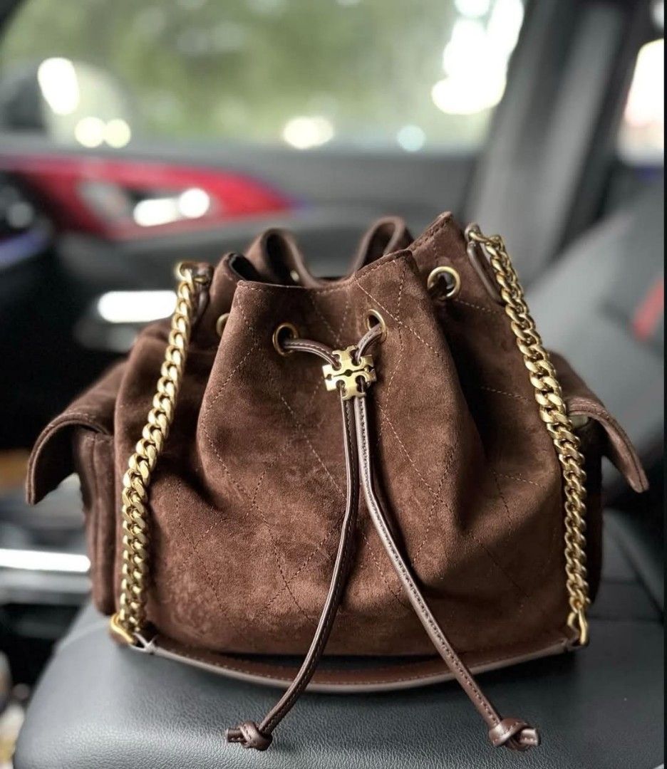 Tory Burch Brown Suede Bucket Bag (Category: Luxury Bags & Wallets) located in Paoay. Submitted by rvf1230 (Listing ID 1464977066, Image 1). Description: - Brand: Tory Burch bucket bag - Material: Rich brown suede with quilted diamond pattern - Hardware: Gold-tone accents and logo - Strap: Mixed chain and leather shoulder strap - Closure: Drawstring closure - Pockets: Two exterior side pockets with flaps and one interior zippered pocket - Conditi