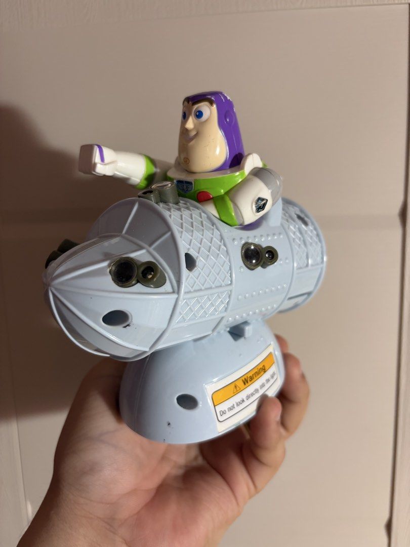 Toy Story Buzz Lightyear Rocket Ship Figure (Category: Figurines & Statues) located in Plaridel. Submitted by moddedjarvis (Listing ID 1465170087, Image 2). Description: - Character: Buzz Lightyear sitting on a blue rocket ship projector toy - Unique Details: Includes a 'Hammer Time' sticker on the base, lens details on the body, and a warning sticker on the back - Condition: Pre-loved, great display piece - Perfect For: Toy Story fans, kids, and