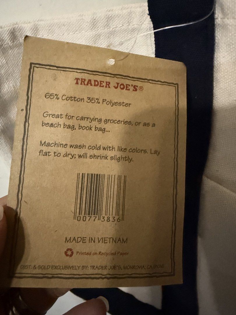 Trader Joe's Reusable Canvas Tote Bag (Category: Tote Bags) located in Quezon City. Submitted by kcobs (Listing ID 1465084115, Image 3). Description: - Authentic Trader Joe's canvas tote bag with original paper hang tag attached - Colorway: Off-white body with stylish navy blue handles and bottom block - Features a handy outer pocket with the embroidered Trader Joe's grocery round logo in red - Material: Durable blend of 65% cotton and 35% polyes