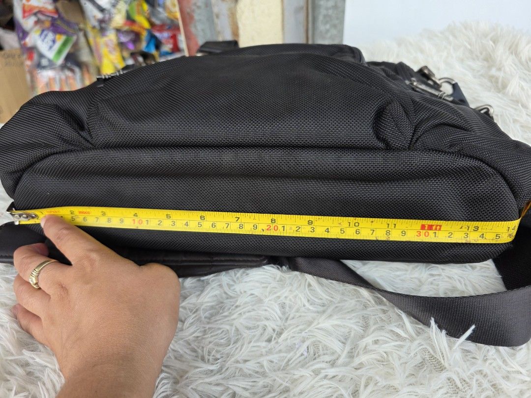 Tumi Black Nylon Briefcase Crossbody Bag (Category: Sling Bags) located in Lemery. Submitted by venus23 (Listing ID 1465098783, Image 3). Description: - Brand: Tumi - Material: Durable ballistic-style nylon with leather trim - Color: Classic Black - Dimensions: Approx. 14 inches across the bottom - Exterior: Multiple zipper pockets and compartments for easy organization - Carry Options: Sturdy leather top handles and a detachable shoulder strap -