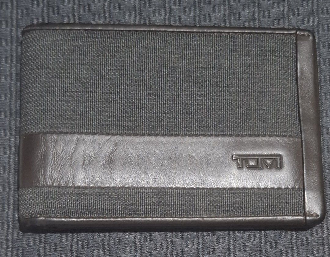 Tumi Brown Leather and Canvas Bifold Wallet (Category: Wallets & Card Holders) located in Makati City. Submitted by decluttermp (Listing ID 1464984735, Image 1). Description: - Authentic TUMI bifold wallet - Dark brown leather and durable textured fabric - Features front stripe with metal TUMI logo - Multiple card slots and full-length cash compartment - Compact size fits easily in back pockets - Clean interior and exterior stitching - Excellent 