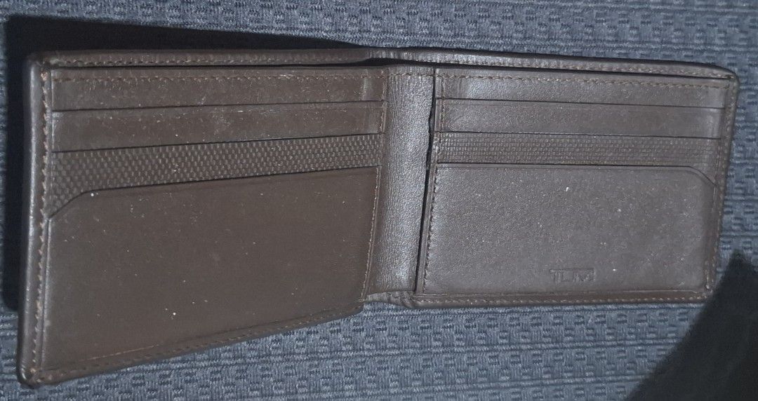 Tumi Brown Leather and Canvas Bifold Wallet (Category: Wallets & Card Holders) located in Makati City. Submitted by decluttermp (Listing ID 1464984735, Image 3). Description: - Authentic TUMI bifold wallet - Dark brown leather and durable textured fabric - Features front stripe with metal TUMI logo - Multiple card slots and full-length cash compartment - Compact size fits easily in back pockets - Clean interior and exterior stitching - Excellent 
