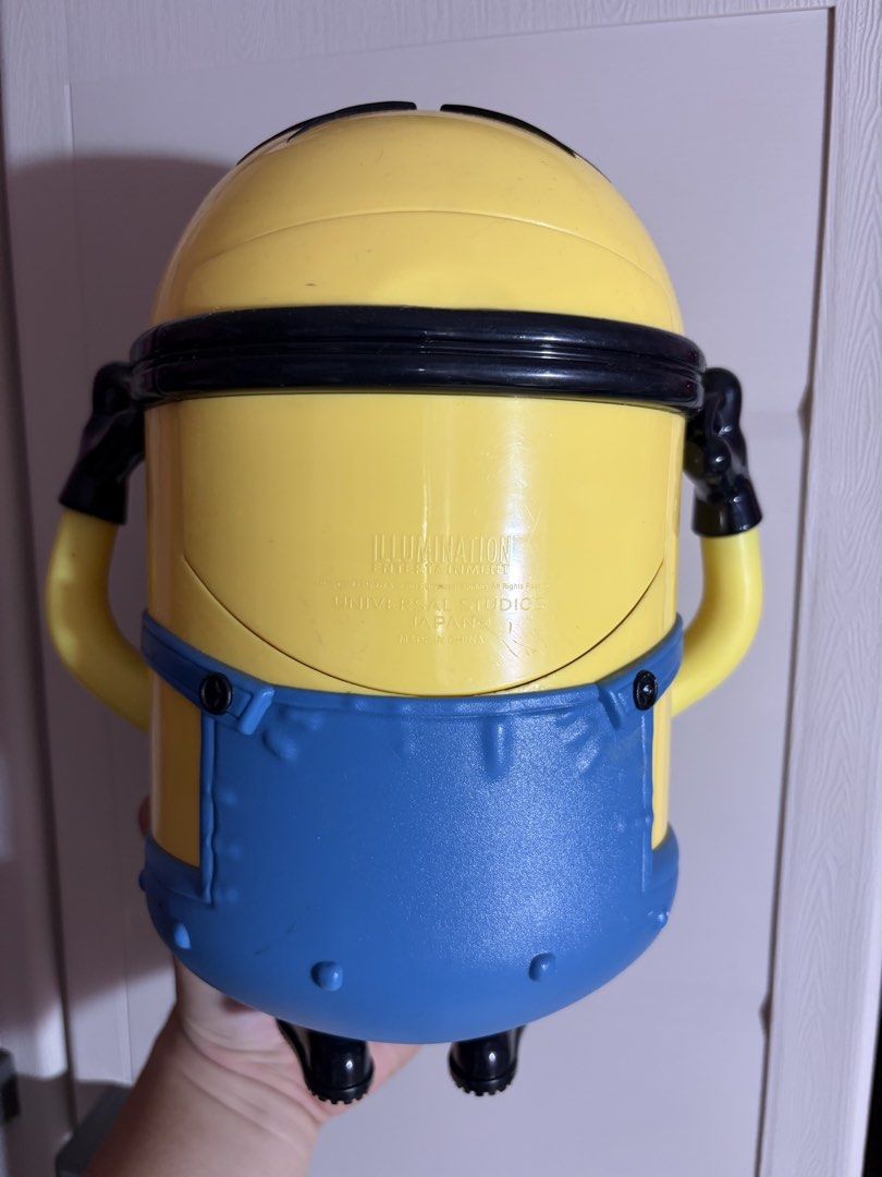 Universal Studios Japan Minion Popcorn Bucket (Category: Character Goods) located in Plaridel. Submitted by moddedjarvis (Listing ID 1465170585, Image 2). Description: - Authentic Universal Studios Japan merchandise -Complete with USJ lace -Issue: yellowish eyes - Iconic Minion character design with large silver goggles - Open-mouth top lid mechanism - Comes with original themed carrying strap - Must-have collectible for Despicable Me fans.