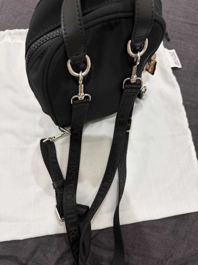 Versace Jeans Couture Nylon Backpack (Category: Luxury Bags & Wallets) located in Makati City. Submitted by konomi.phh (Listing ID 1465084393, Image 2). Description: - Brand: Versace Jeans Couture - Material: Durable black nylon with monogram fabric lining - Hardware: Silver metal logo plaque on front pocket - Straps: Adjustable branded webbing straps and top handle - Inclusions: Original dust bag and brand tags attached - Condition: Brand new - 