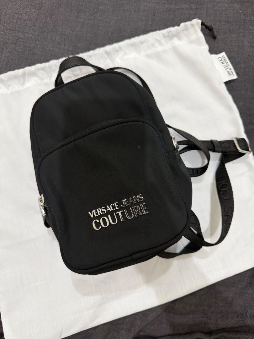 Versace Jeans Couture Nylon Backpack (Category: Luxury Bags & Wallets) located in Makati City. Submitted by konomi.phh (Listing ID 1465084393, Image 1). Description: - Brand: Versace Jeans Couture - Material: Durable black nylon with monogram fabric lining - Hardware: Silver metal logo plaque on front pocket - Straps: Adjustable branded webbing straps and top handle - Inclusions: Original dust bag and brand tags attached - Condition: Brand new - 