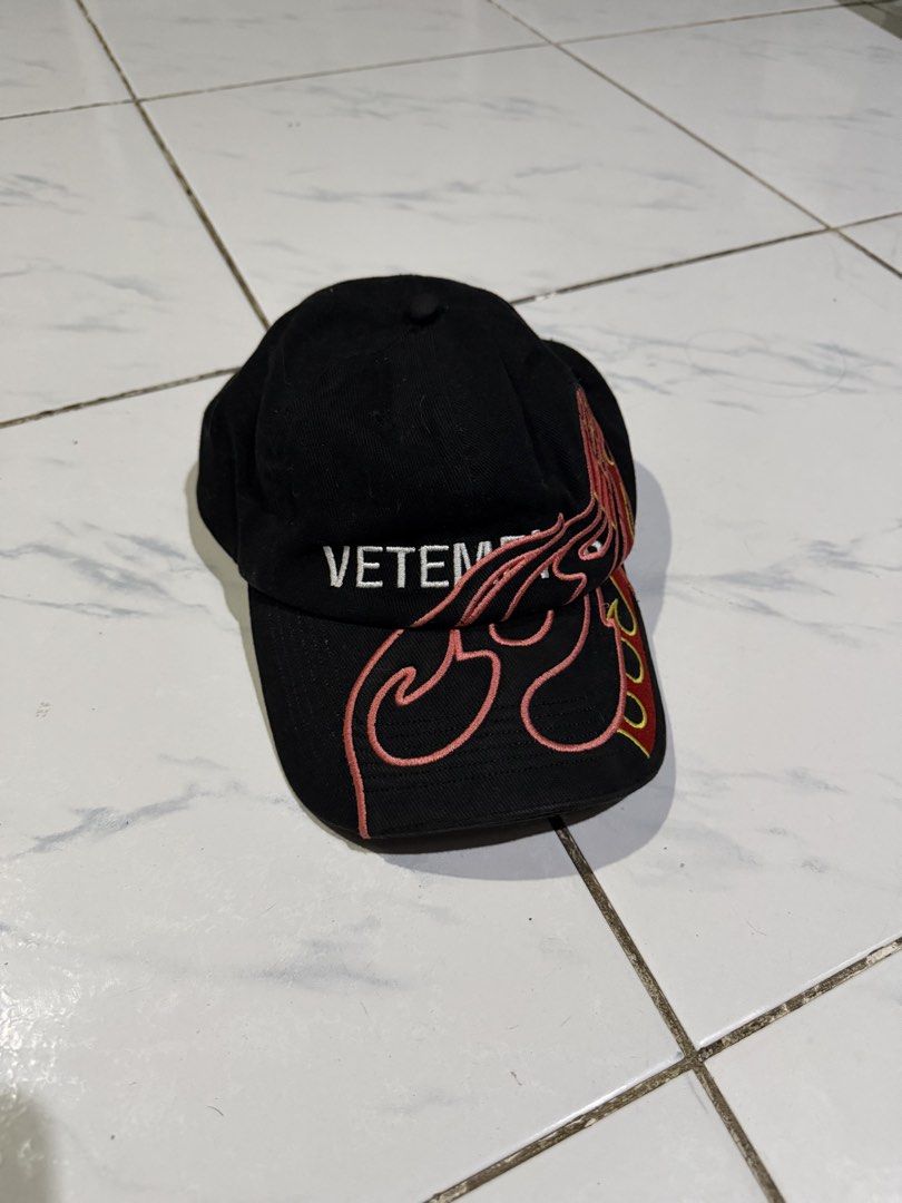 VETEMENTS Flame Embroidered Baseball Cap Black (Category: Caps & Hats) located in Manila. Submitted by skeletal_v2 (Listing ID 1465102416, Image 1). Description: - Brand: Vetements - Material: 100% Cotton - Color: Black with vibrant pink and yellow flame embroidery - Details: Signature white Vetements logo on the front panel - Fit: Adjustable strap closure in the back for a custom fit - Condition: Clean overall condition, ready to wear - Inclusio