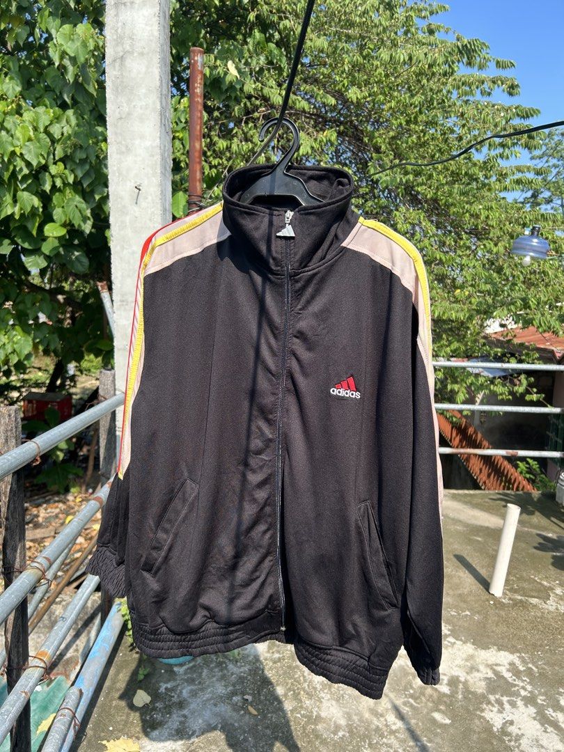 Vintage Adidas Black Track Jacket Size M (Category: Coats, Jackets and Outerwear) located in Cebu City. Submitted by purephoenix-2e10a3 (Listing ID 1464972971, Image 1). Description: - Brand: Adidas - Style: Black track jacket with beige chest and shoulder panels - Details: Colorful stripes on sleeves, red embroidered Adidas logo - Hardware: Custom metal zipper pull shaped like the Adidas trefoil logo - Size: Medium - Features: Full zip closure, 