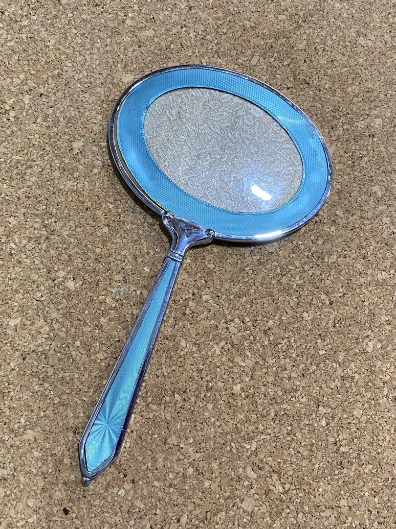 Vintage Art Deco Vanity Hand Mirror (Category: Mirrors) located in Calamba. Submitted by chebvintagedepot (Listing ID 1465033431, Image 1). Description: [B29-04] This vintage Art Deco-style hand mirror has an oval shape with an ornate handle and a guilloché finish. The silver-tone metal frame is complemented by a decorative floral-patterned back panel with a protective cover. The combination gives the mirror a classic vintage vanity look inspired