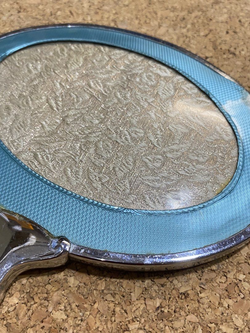 Vintage Art Deco Vanity Hand Mirror (Category: Mirrors) located in Calamba. Submitted by chebvintagedepot (Listing ID 1465033431, Image 2). Description: [B29-04] This vintage Art Deco-style hand mirror has an oval shape with an ornate handle and a guilloché finish. The silver-tone metal frame is complemented by a decorative floral-patterned back panel with a protective cover. The combination gives the mirror a classic vintage vanity look inspired