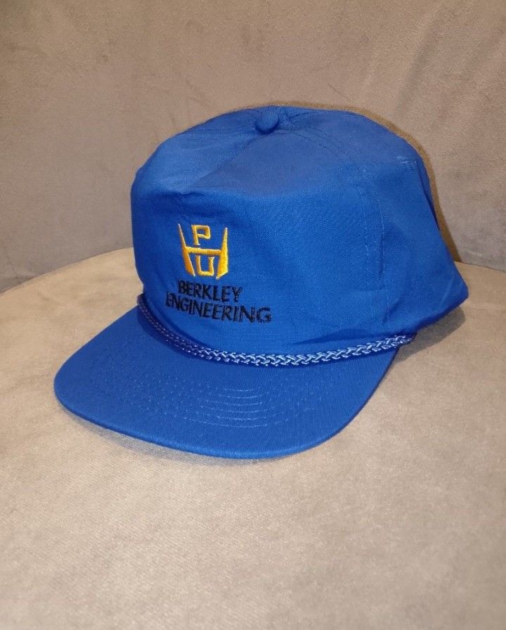 Vintage Berkley Engineering Snapback Hat, Blue with Yellow Logo (Category: Caps & Hats) located in Binangonan. Submitted by yuristalin888 (Listing ID 1464973369, Image 2). Description: This vintage blue snapback hat features the "Berkley Engineering" logo embroidered in yellow on the front. The hat has a classic five-panel construction with a rope detail across the brim. It is made of a sturdy fabric and includes an adjustable strap and brass-ton