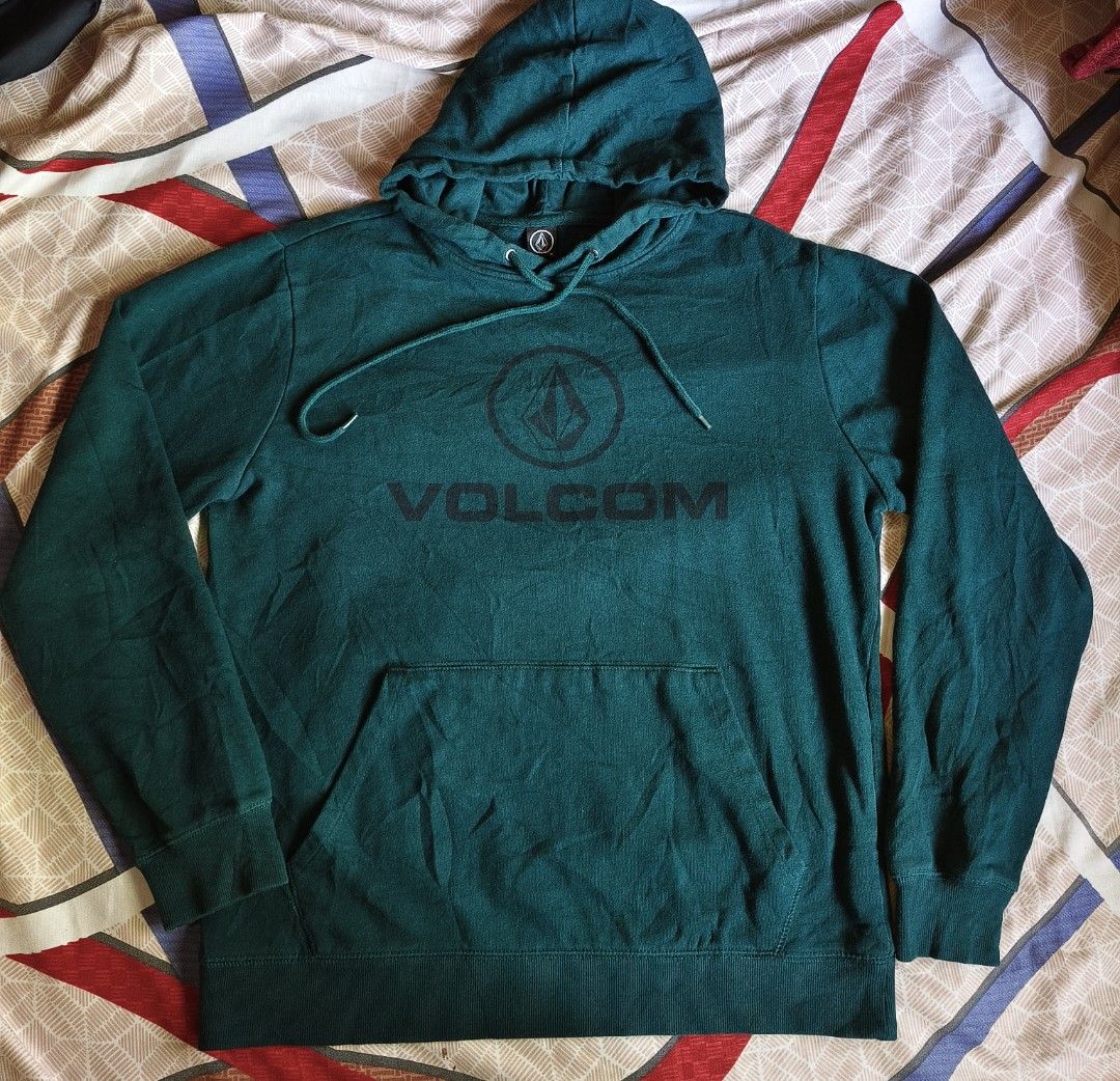 Volcom Green Hoodie Sweatshirt Size M (Category: Coats, Jackets and Outerwear) located in Baguio. Submitted by thriftjc (Listing ID 1464973364, Image 3). Description: - Brand: Volcom - Color: Dark green - Size: M (tagged on collar) - Material: 60% cotton, 40% polyester - Design: Big stone logo printed on the chest - Features: Kangaroo front pocket, adjustable drawstring hood, ribbed cuffs and hem - Origin: Made in China.