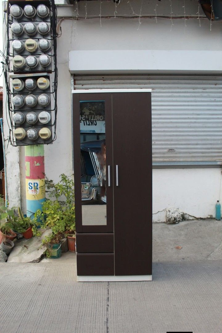 Wardrobe (Category: Shelves, Cabinets & Racks) located in Meycauayan. Submitted by marygracecasimiro (Listing ID 1465115939, Image 3). Description: Modern 2-Door Wardrobe with Mirror Dark wenge finish with a full-length mirror, two bottom drawers and spacious hanging compartments. Finished with sleek silver handles and white-colored accents. Perfect for bedrooms and compact spaces L:31 ¼ • W:21 ½ • H:79 inches 12,700 pesos only♥️.