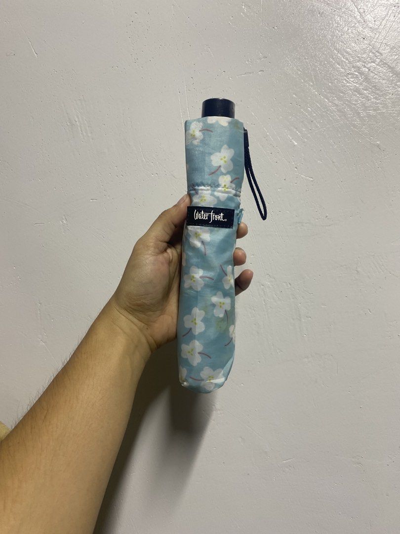 Waterfront Floral Folding Umbrella UV Protected (Category: Umbrellas) located in Pasacao. Submitted by wengpullar37205 (Listing ID 1465096915, Image 1). Description: - Color/Design: Light blue with white cherry blossom flowers - Protection: UV protection coating on the handle for sun and rain - Portable: Folds down small into a matching printed sleeve with a wrist strap - Convenience: Compact size, easy to toss into any bag - Brand: WaterFront.
