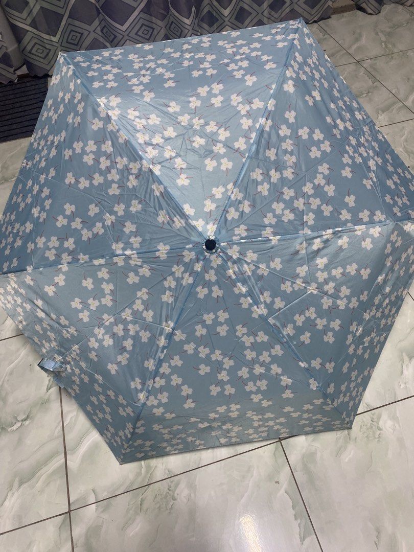 Waterfront Floral Folding Umbrella UV Protected (Category: Umbrellas) located in Pasacao. Submitted by wengpullar37205 (Listing ID 1465096915, Image 3). Description: - Color/Design: Light blue with white cherry blossom flowers - Protection: UV protection coating on the handle for sun and rain - Portable: Folds down small into a matching printed sleeve with a wrist strap - Convenience: Compact size, easy to toss into any bag - Brand: WaterFront.