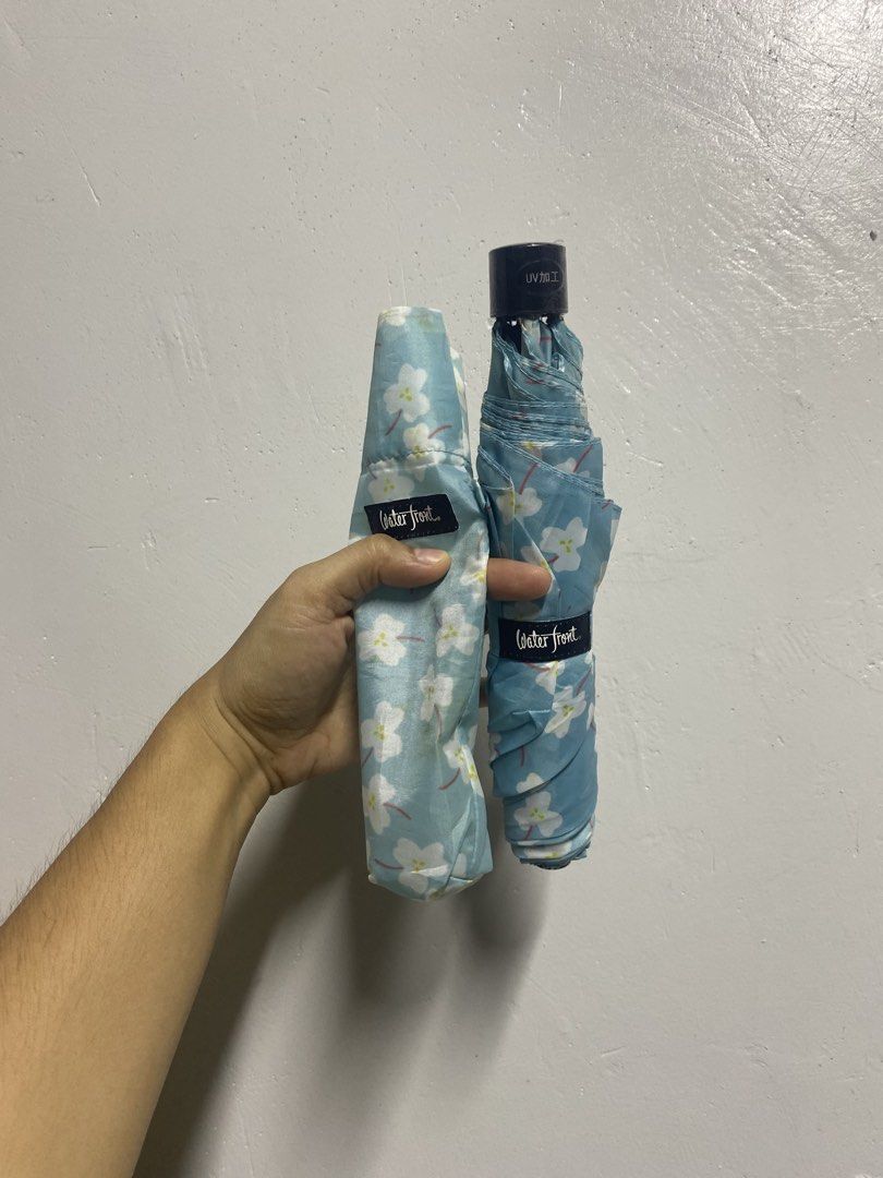 Waterfront Floral Folding Umbrella UV Protected (Category: Umbrellas) located in Pasacao. Submitted by wengpullar37205 (Listing ID 1465096915, Image 2). Description: - Color/Design: Light blue with white cherry blossom flowers - Protection: UV protection coating on the handle for sun and rain - Portable: Folds down small into a matching printed sleeve with a wrist strap - Convenience: Compact size, easy to toss into any bag - Brand: WaterFront.