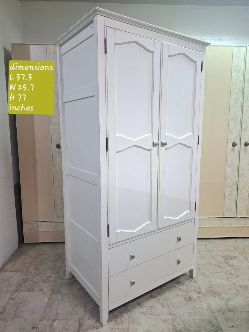 White 2-Door Wardrobe with Double Bottom Drawers (Category: Shelves, Cabinets & Racks) located in Quezon City. Submitted by japandemanila (Listing ID 1465007758, Image 1). Description: - Color: Solid white - Material: Sturdy wood with metal knobs - Storage: Double doors, interior hanging rail, and upper shelf - Drawers: Two large pull-out drawers at the bottom - Design: Elegant decorative molding on doors - Condition: Clean interior and very stur