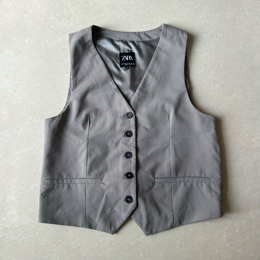Zara Grey Tailored Button-Down Vest Top (Category: Sleeveless) located in Paranaque City. Submitted by yanie.ae (Listing ID 1464984524, Image 1). Description: - Brand: Zara - Color: Grey - Design: V-neck with 5 black front buttons and 2 functional welt pockets - Lining: Fully lined with a chic striped interior fabric - Origin: Made in Turkey - Condition: Clean and ready to wear.