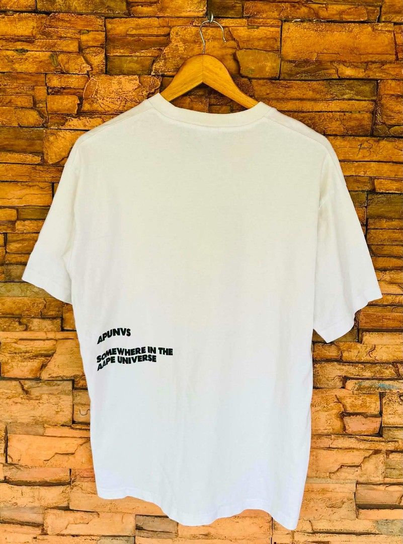 AAPE by A Bathing Ape Graphic T-Shirt Size L (Category: Tshirts & Polo Shirts ) located in Santiago. Submitted by reyibanez253969 (Listing ID 1459501708, Image 2). Description: - White AAPE t-shirt - Size: Large (L) - 22x28.5 - Front graphic featuring AAPE logo and character design - Text detail on the back - Ideal for casual wear.
