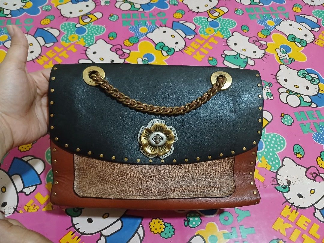 Authentic Coach Parker Leather Chain Shoulder Bag (Category: Luxury Bags & Wallets) located in Manila. Submitted by pretty0099 (Listing ID 1459612770, Image 1). Description: - Authentic Coach Parker Sling Bag - Genuine leather shoulder bag in black and brown - Elegant chain strap - Decorative flower detail on the front - Convenient pocket on the back with Coach signature pattern - Unique snake print interior lining - Includes original Coach leath