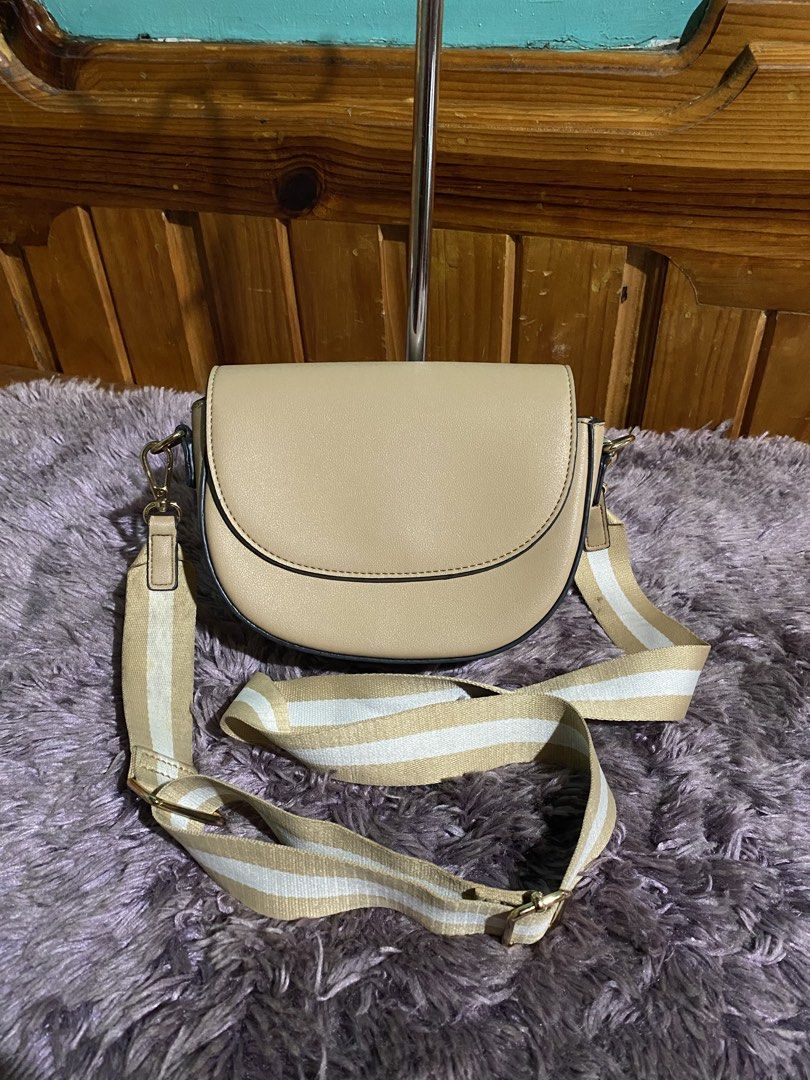 Beige Crossbody Bag with Striped Strap (Category: Cross-body Bags) located in La Trinidad. Submitted by kinleyky (Listing ID 1459617911, Image 3). Description: - Cute beige crossbody bag - Curved flap closure with magnetic snap - Main compartment and interior zippered pocket - Adjustable strap with stylish beige and white stripe pattern - Gold hardware details - Ideal for everyday use.