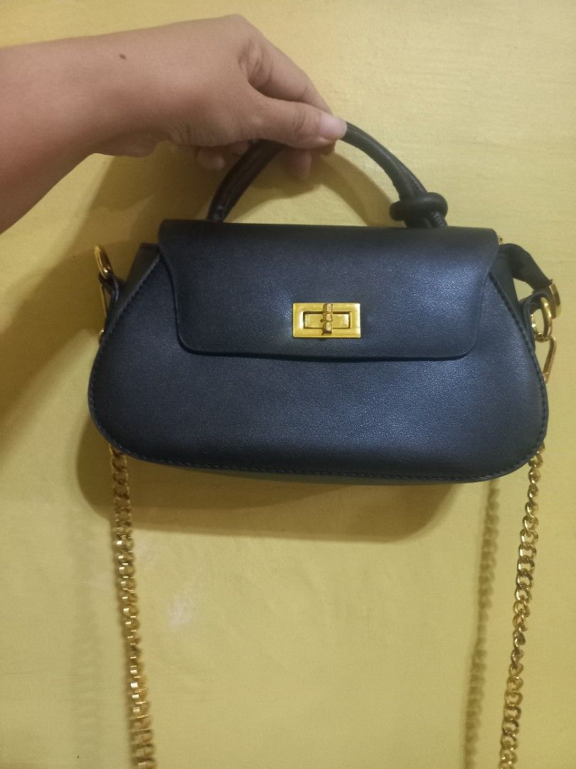 Black Handbag with Gold Clasp and Chain Strap (Category: Cross-body Bags) located in Manila. Submitted by mrose_2412 (Listing ID 1459583969, Image 3). Description: ⭐️Brand: Parisian ⭐️ Condition: Brand New (Never used) ⭐️ Color: Classic Black with Gold-tone Hardware Design Features: ⭐️ Curved structured silhouette with a top flap ⭐️ Twist-lock front accent closure ⭐️ Top handle with knot accent for hand-carrying .