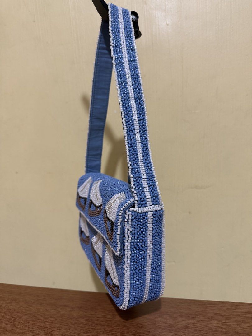 Blue Beaded Handbag with Ice Skate Design (Category: Clutches) located in Cavite. Submitted by disneygirl27 (Listing ID 1459597690, Image 2). Description: - Adorable blue shoulder bag - Covered in beads with a charming ice skate pattern - Beaded strap for a cohesive look - Secure zipper closure - Includes a small inner pocket for essentials - Crafted from 100% polyester - A delightful and fun accessory to elevate your style.