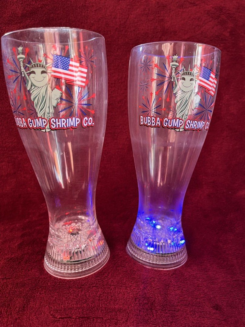 Bubba Gump Shrimp Co. Light-Up Plastic Glasses Set (Category: Other Home Decor) located in La Trinidad. Submitted by whatnotcollections (Listing ID 1459600304, Image 2). Description: - Set of 2 clear plastic glasses from Bubba Gump Shrimp Co. - Features Statue of Liberty graphic with American flags and fireworks. - Bases light up with LEDs: red, green & blue. The other cup only lights up red. -The glasses are approximately 7-5/8 inches tall and m