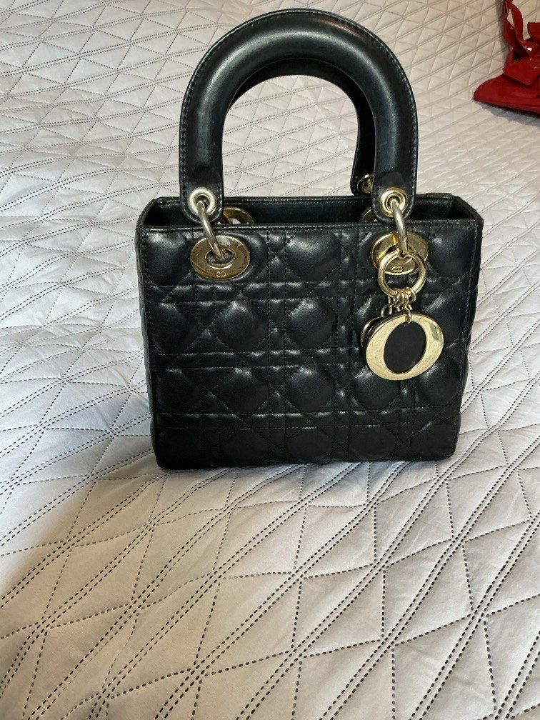 Lady Dior Bag (Category: Purses & Pouches) located in Makati City. Submitted by boldturtle-8720 (Listing ID 1459544674, Image 2). Description: Classic black lambskin Lady Dior bag accented with signature pale gold-tone hanging charms. Bag with *asterisk is the one for sale. Left bag (authentic) is for comparison only. ‘OG’ quality Includes box and dust bag. Negotiable. .