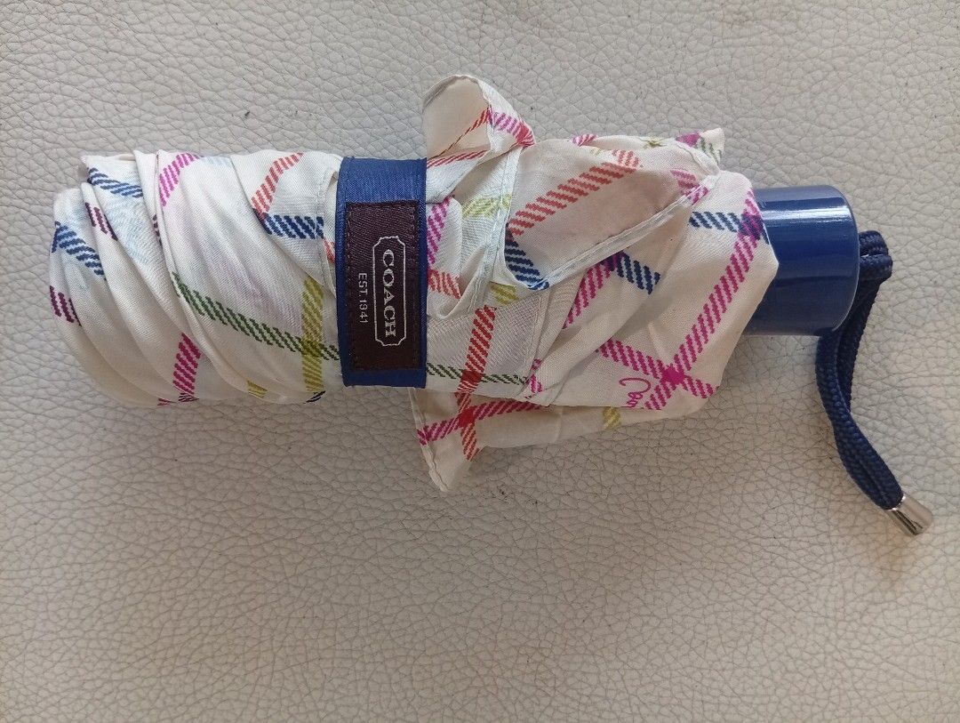 Coach Plaid Folding Umbrella (Category: Umbrellas) located in Davao. Submitted by lingxu23 (Listing ID 1459505106, Image 1). Description: - Authentic Coach folding umbrella - Eye-catching colorful plaid pattern - Compact and portable design, ideal for everyday carry - Features a stylish blue handle and strap - Secure snap closure - Coach logo detail on the strap - Essential for staying dry on rainy days.