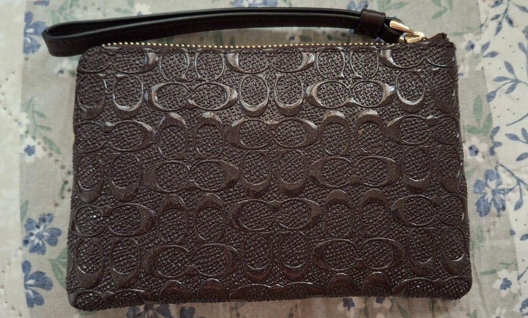Coach Signature Monogram Embossed Leather Wristlet Pouch (Category: Luxury Bags & Wallets) located in Balete. Submitted by vastfish.a46383 (Listing ID 1459536598, Image 2). Description: - Dark purple glim Coach wristlet - Signature C monogram embossed all over - Leather material with a subtle sheen - Features a wrist strap - Zip closure - Interior card slots - Ideal for carrying essentials.
