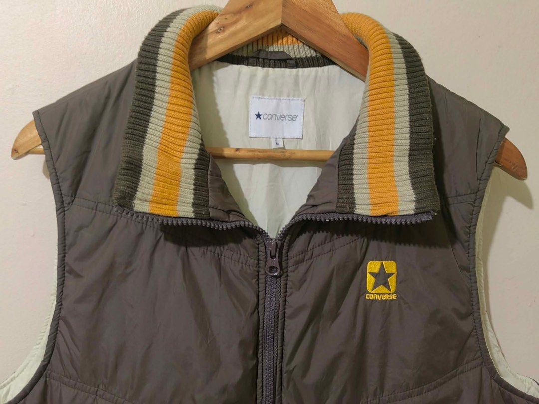 Converse Puffer Vest Size L (Category: Vests) located in General Trias. Submitted by lyzcollections. (Listing ID 1459689134, Image 2). Description: - Converse puffer vest - Color: Brown - Features classic Converse star logo on chest - Ribbed collar and hem with yellow and grey stripes - Ideal for layering - Size: L.