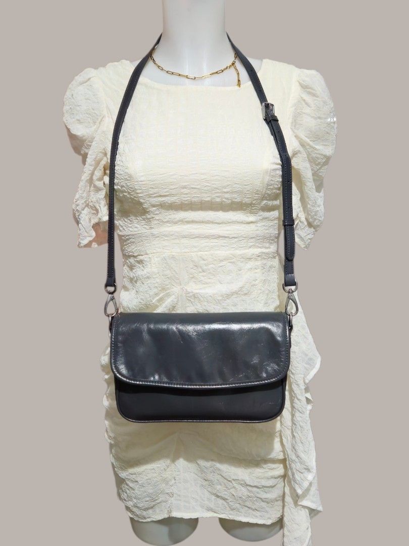 Dark Grey Leather Crossbody Shoulder Bag (Category: Cross-body Bags) located in Quezon City. Submitted by kirstenbella (Listing ID 1459548541, Image 2). Description: Dark grey leather crossbody bag - Made of pure genuine leather - Shinny texture - Zip pocket on the back - Adjustable strap with buckle - Silver hardware - Can be worn on shoulder or crossbody - Dimensions H 6.5" x L 10" x D 2.5" - Spacious compartment with inner pockets - NO Issue a