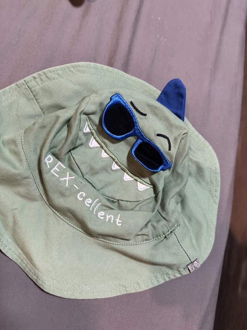 Flapjack Kids Reversible Dinosaur Bucket Hat (Category: Babies & Kids Fashion) located in Leyte. Submitted by handmedownp (Listing ID 1459588803, Image 3). Description: - Super cute reversible bucket hat for kids. - Side 1: Green dinosaur face with sunglasses and 'REX-cellent' text. - Side 2: Denim blue with a surfing dinosaur and 'RAWR-some' text. - Ideal for sunny days and sun protection. - Fun and playful design for children. - no stains, disc